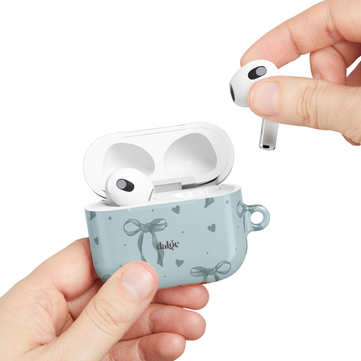 Wireless earbuds in a blue case with decorative elements, held by a hand against a white background.