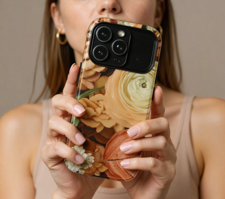 Woman holding a phone with a floral case against a neutral background 