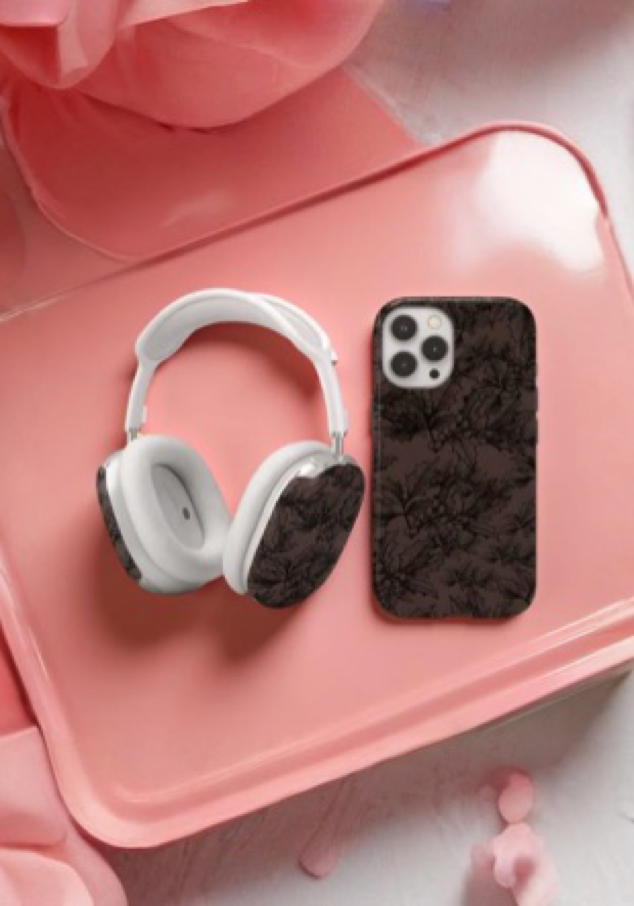 White headphones With designed dark floral cases and a phone with dark floral case on a pink surface
