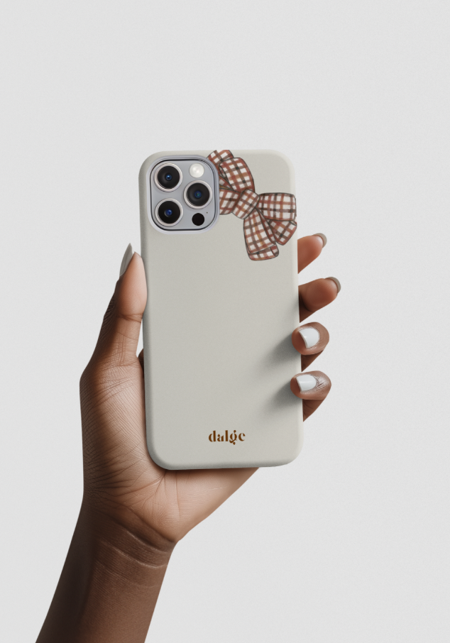 Phone case with a brown plaid bow design held by a hand on a light background, fall designed phone case from Toffee Latte Collection