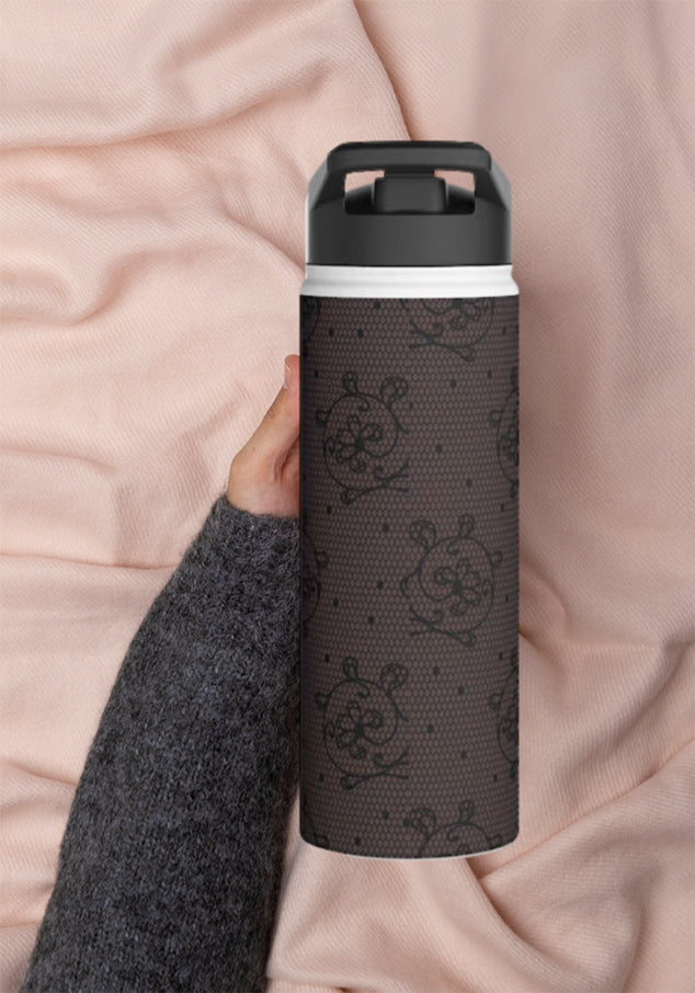 Hand holding a water bottle with dark lace design on a silk baby pink background